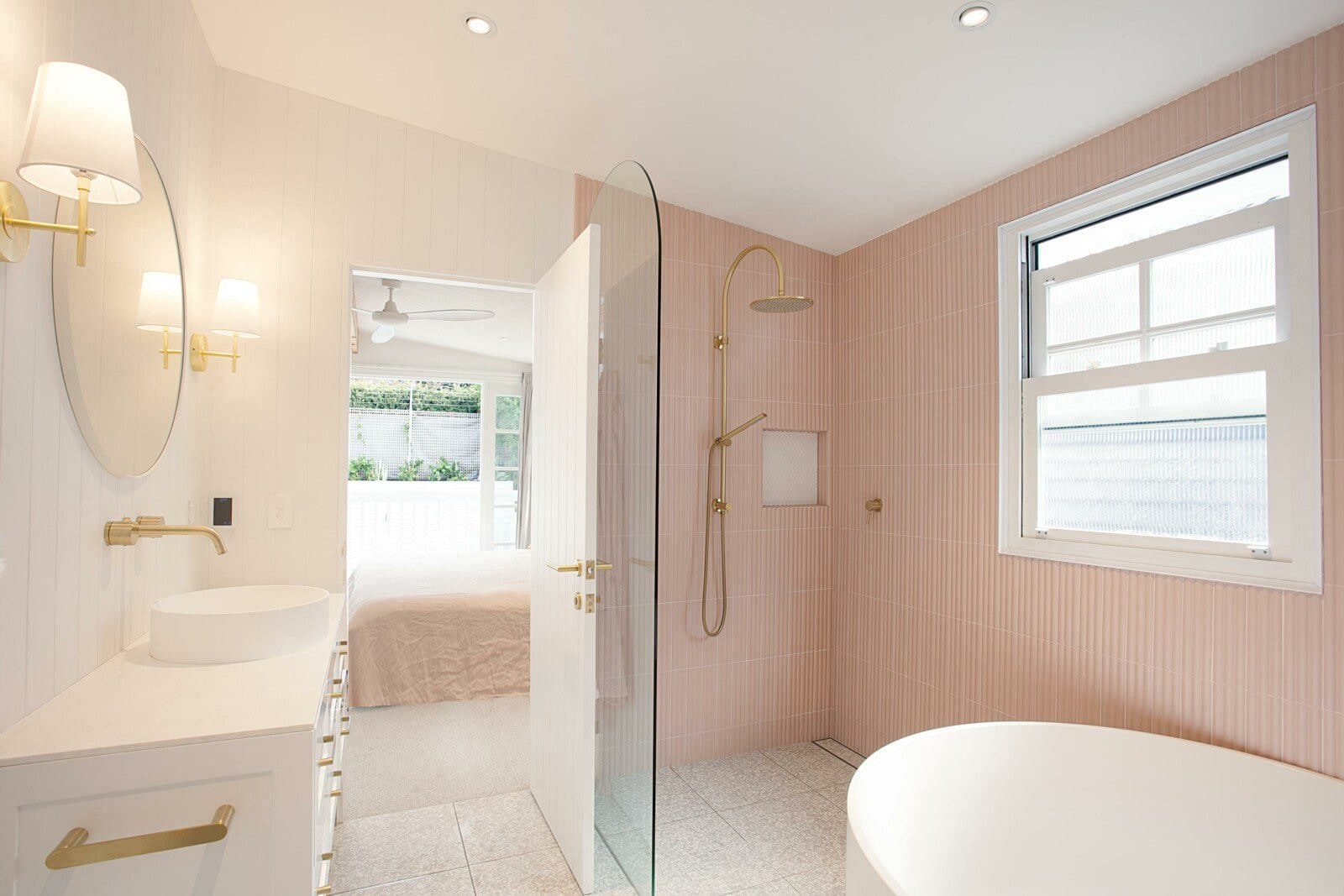 Ensuite with pink vertical tiles, brass fittings, a freestanding bath and a walk-in shower