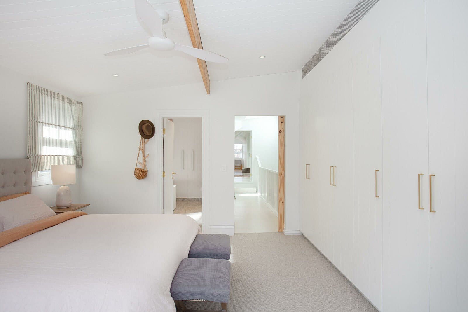 Main bedroom with full-height white built-in wardrobes and an exposed timber beam