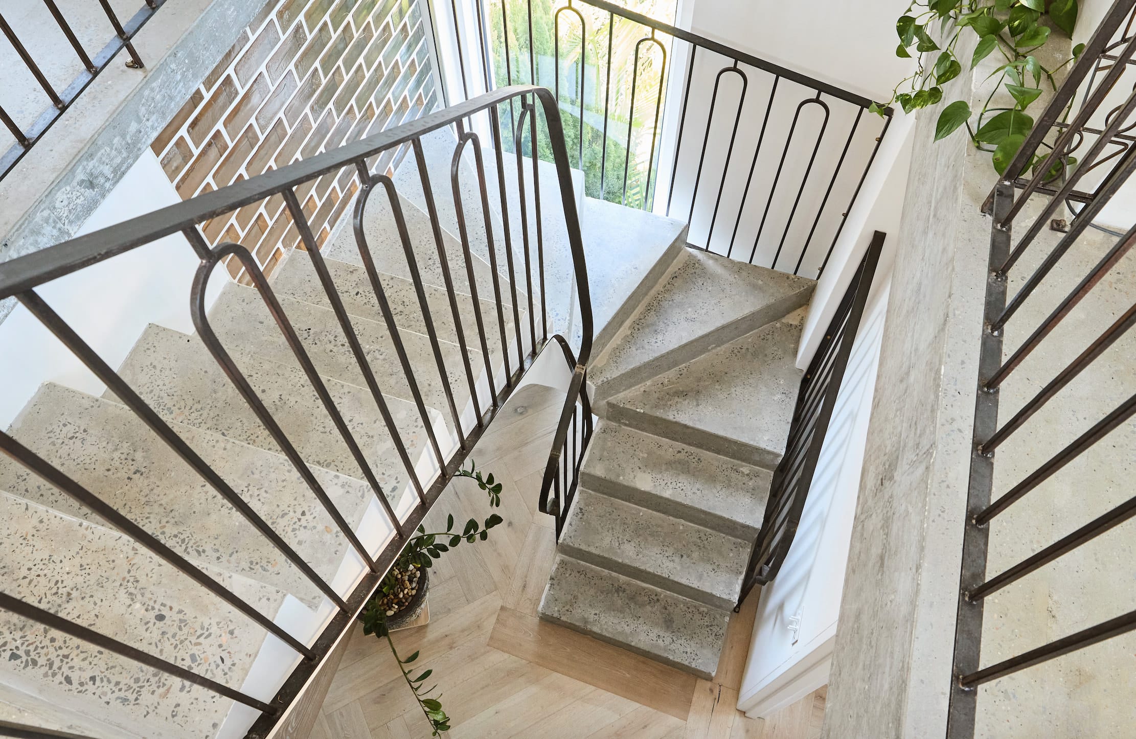 Stairwell seen from above, with speckled stone-look treads and a black steel balustrade